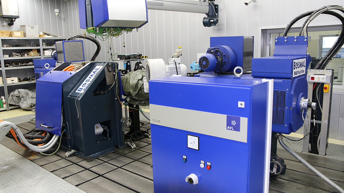 Large blue industrial testing equipment installed in a laboratory, with control units, motors, cables, and measurement systems arranged on a test platform.
