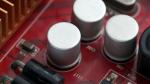 Close-up of capacitors and components on a red electronic motherboard